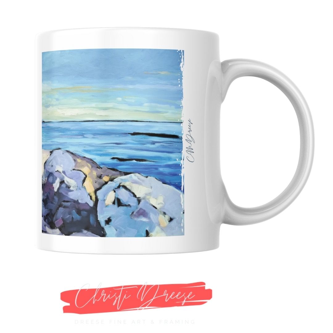 Coffee mug with a scenic design of water and the Michigan shoreline, featuring the artist's signature.